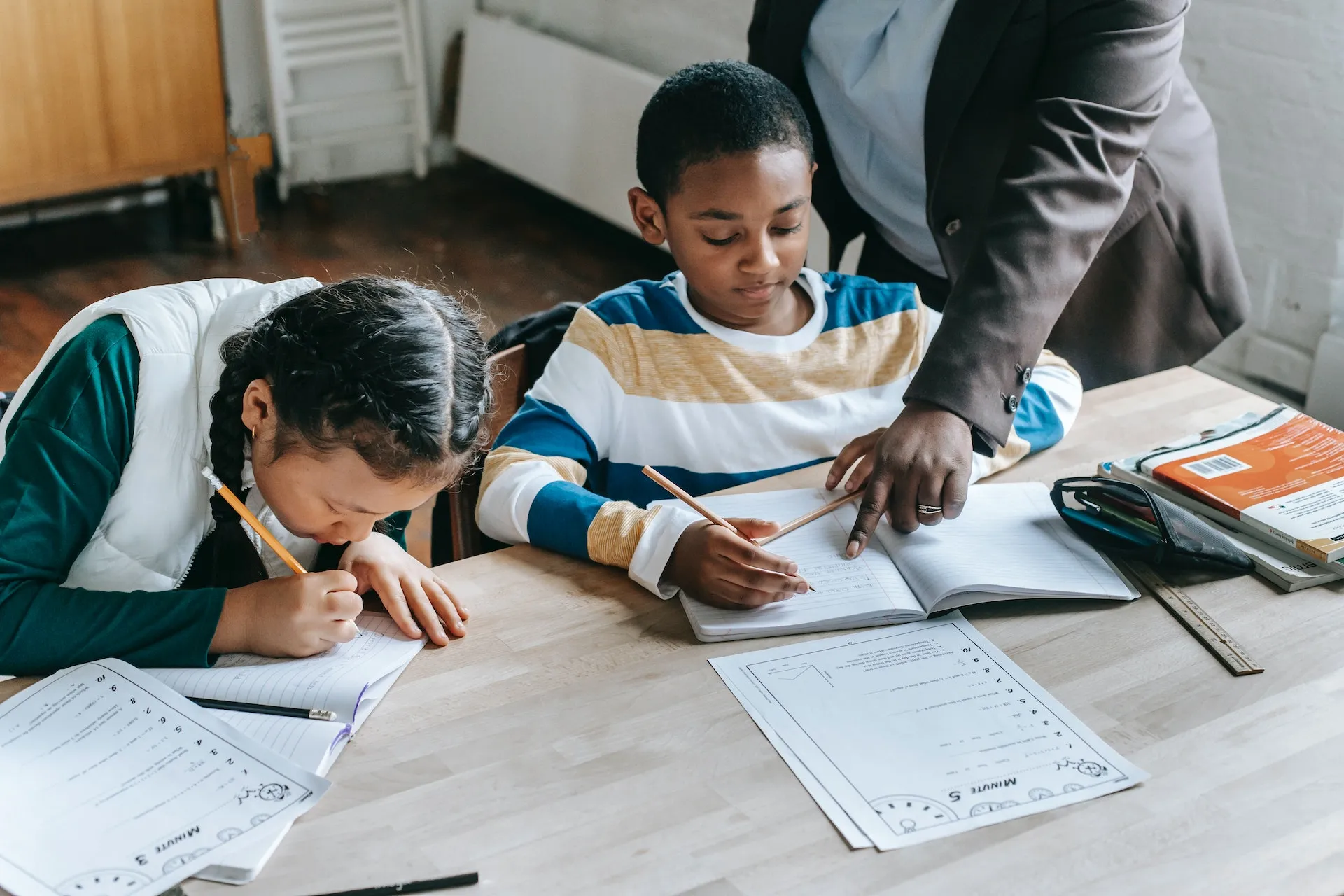 Children practicing writing with a teacher helping